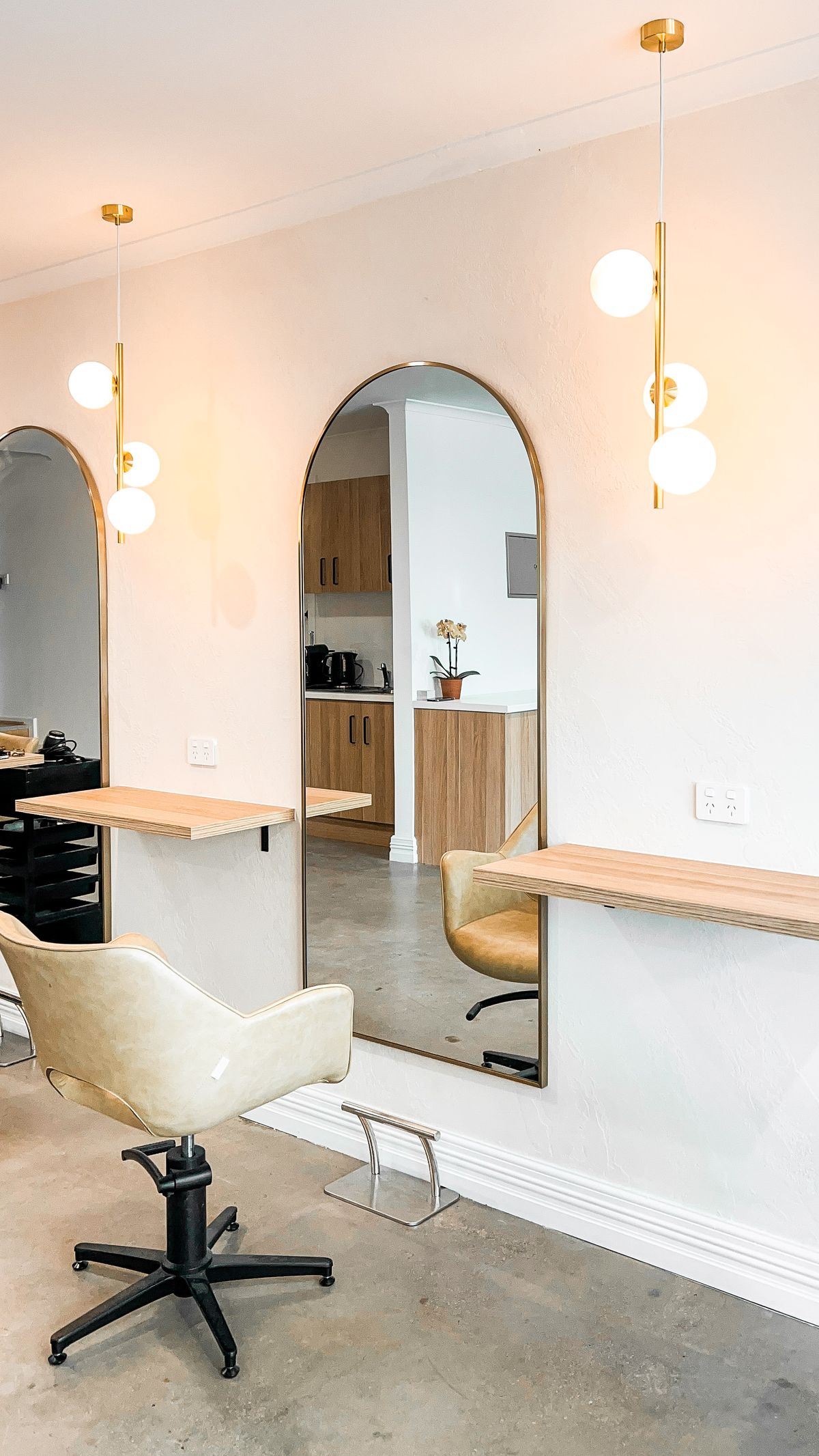 Two styling stations with arched mirrors and brass globe pendant lights